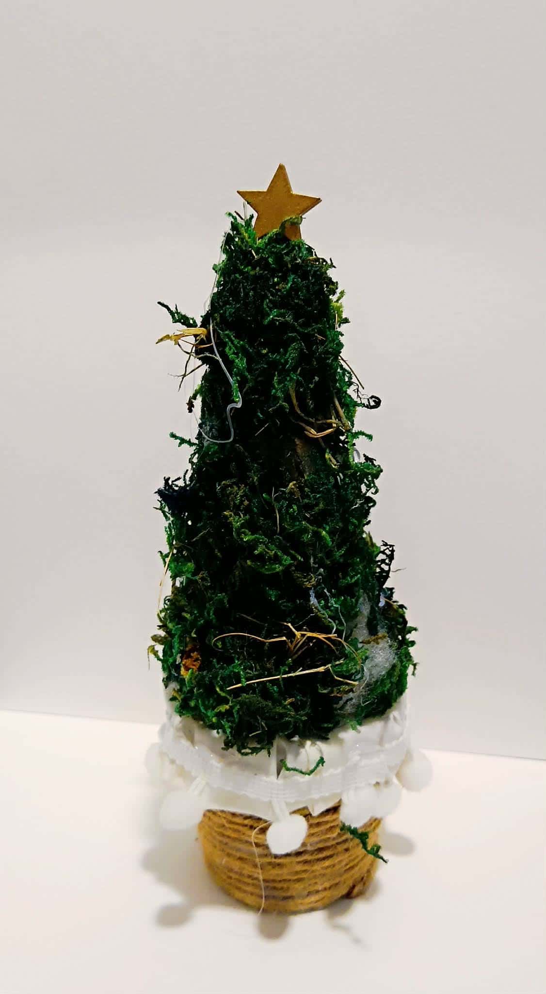 Choinka z mchu z złotą gwiazdką na czubku, ustawiona na podstawce ze sznurka – praca dziecka.