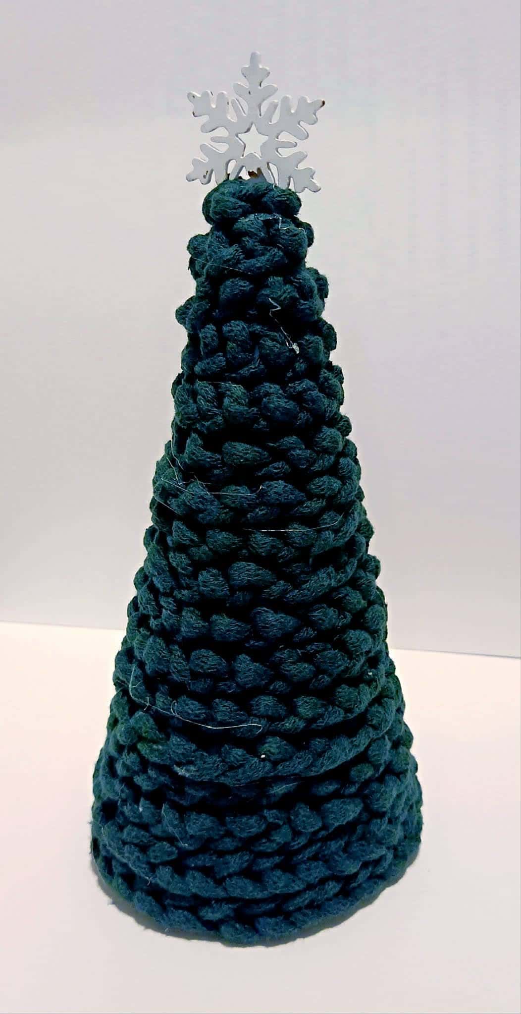 Choinka ze splecionego zielonego sznurka z białą śnieżynką na czubku – praca plastyczna dziecka.