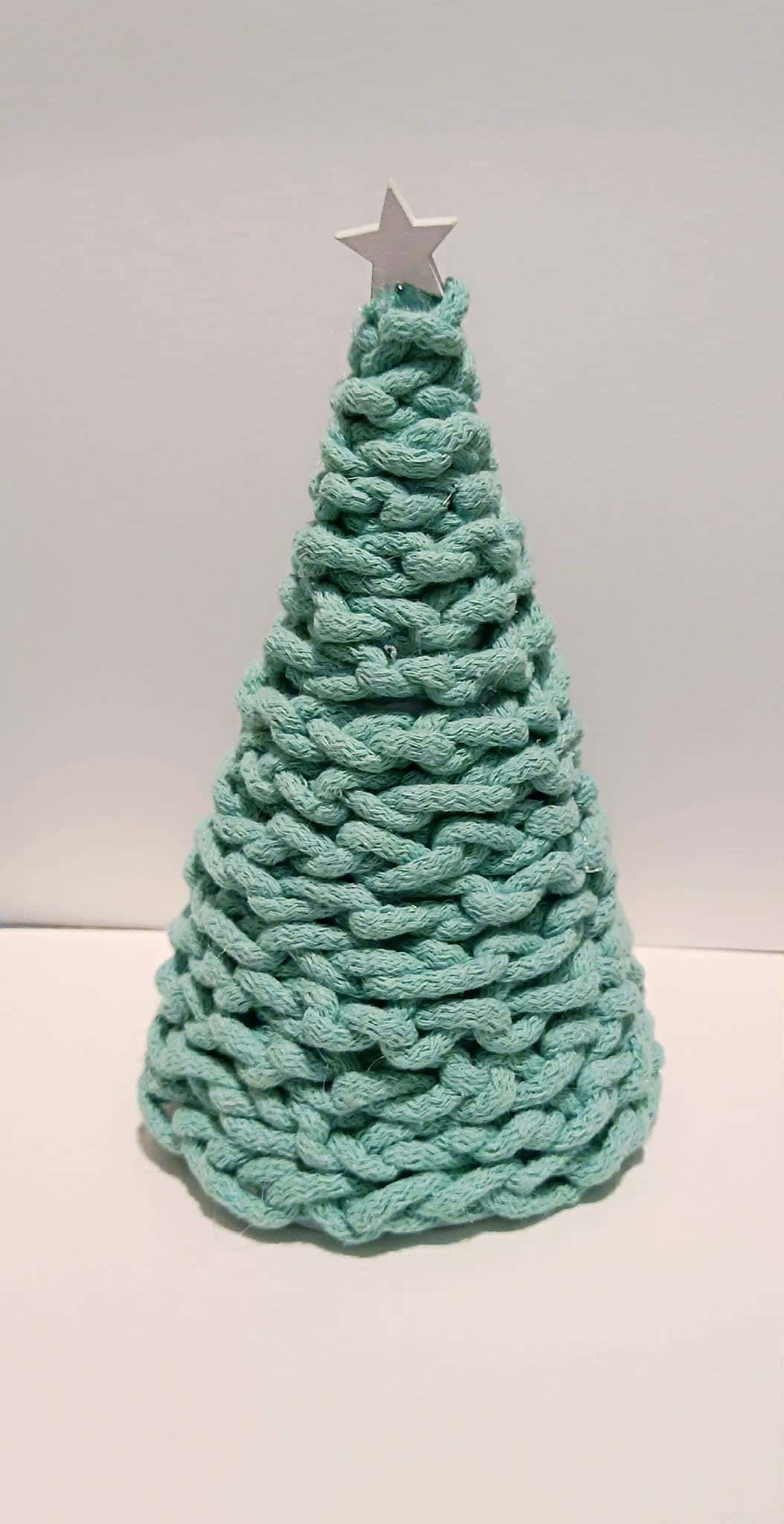 Kolorowa choinka z pasów kredki olejnej na białym tle z gwiazdką i białymi kropkami jak śnieg.